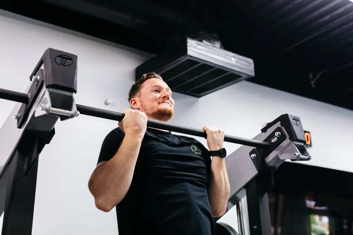 A member finishes a pull-up on the rig during a strength session at an Alloy Personal Training studio