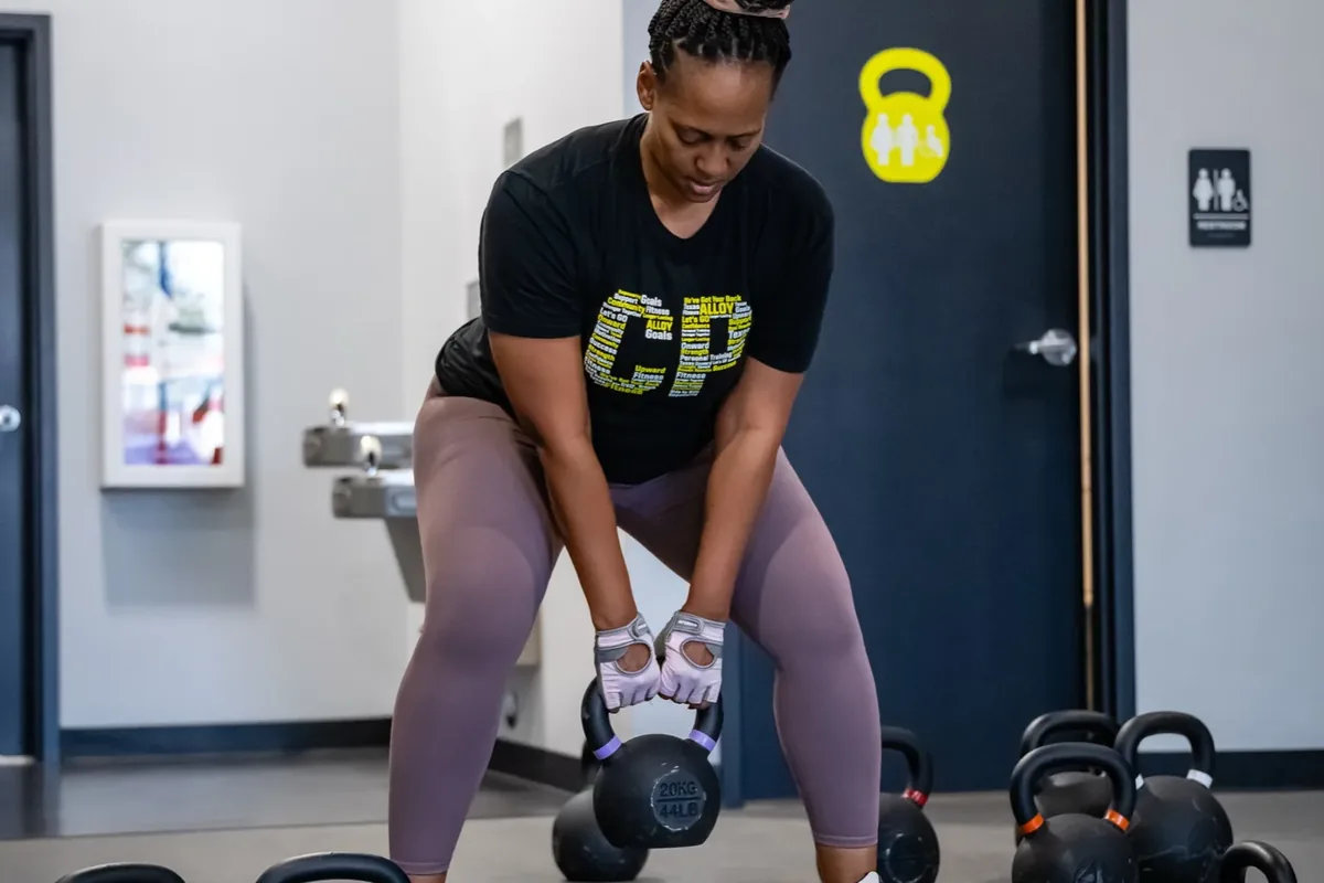 A member lifts a kettlebell from a hinge position on the training floor at Alloy Personal Training Middleton in Middleton, WI.